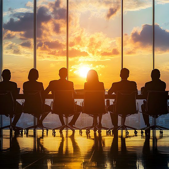 Silhouette of board members overlooking city at sunset