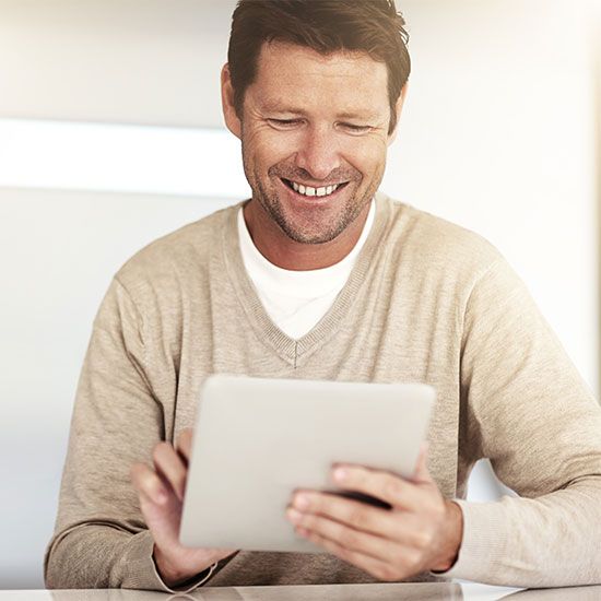 Man smiling while looking at tablet